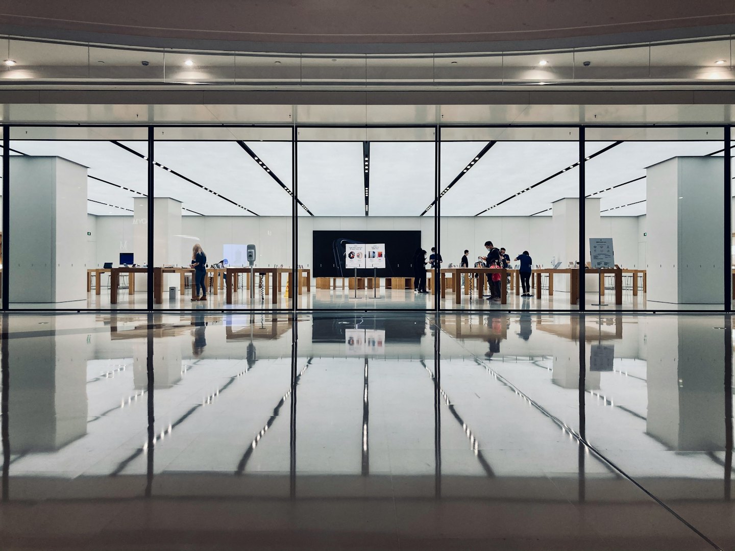 Customers browse products in a bright, modern tech store.